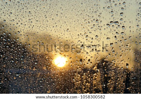 Raindrops on glass and sun at dawn. Weather forecast.