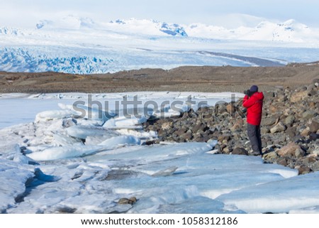man in red warm shirt take photo of Iceland winter landscape with icy snow capped mountain in winter and sunny day.