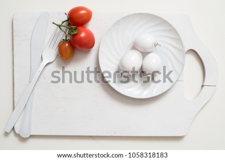 Bunch of tomatoes stock images. White fork knife plate on an old wooden plank tray. Art idea white tomatoes, painted with paint. Bright spot three red tomatoes. art  abstract absurd