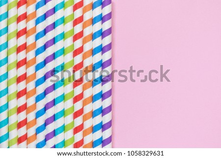 Colorful striped drinking straws on pastel pink background minimal creative concept. Space for copy.
