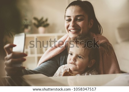 Mother taking self picture of her daughter and her.