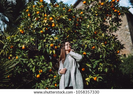 Pretty girl near the mandarin tree. The fruit full of fruit