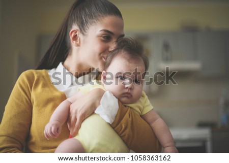 Mother holding her baby and kissing.