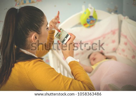 Mother taking picture of her sleeping baby.