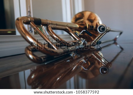 gold musical instrument pipe is on a wooden chest of drawers