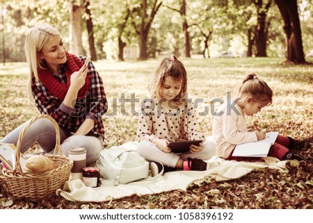 Single mother in park with her daughters taking picture of them.