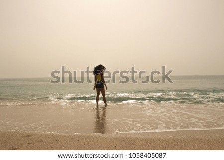 Short Jeans dressed girl standing in middle of beach waves