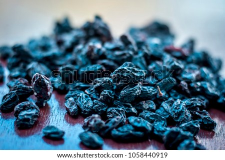 Black raisin or kali kishmish or Zante currant in a white plate on wooden surface in dark Gothic colors to decreases the chance of Dehydration.