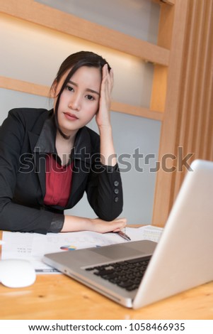 Serious female executive finding ideas while working at her desk with laptop