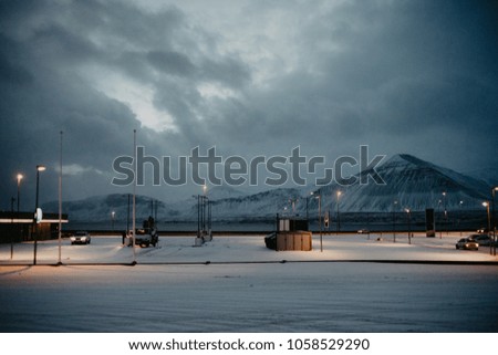 a petrol station in front of some mountains, covered in snow in Iceland just before sunrise