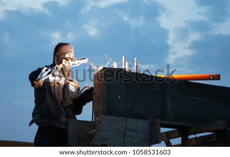 Worker welding steel with bright sparks at construction site