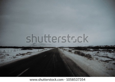 A straight road in Iceland, leading through a snow covered landscape