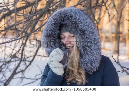 girl warms her hands in mittens, in the winter on the street, outdoors