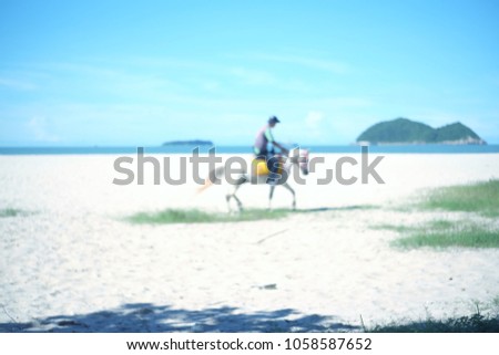 Blurred picture of a man riding a white horse along the beach. At Samila Songkhla Province