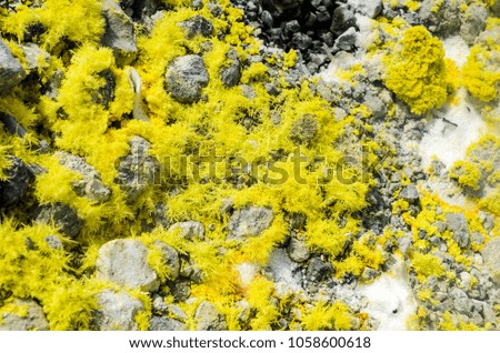 Yellow Sulphur on surface of rocks on top of a volcano crater on the island of Vulcano, Aeolian Archipelago. Sicily, Italy. Gray white and Yellow background of Sulfur. Steam and smoke from fumarole