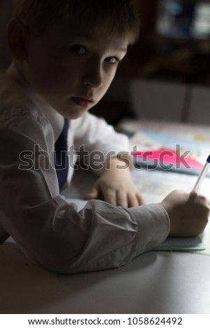 Boy hand with pencil writing english words by hand on traditional white notepad paper. Boy writes a letter to a friend