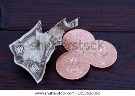 Dollar banknotes and Bitcoins on a dark wooden table