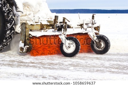 Tractor cleans road from snow after blizzard. Bad winter weather conditions and transport service concept.