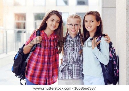 A group of three schoolgirls friends smiling - outdoor picture at the school yard
