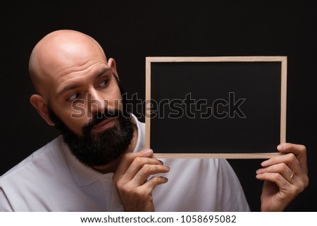 bearded man with black board on black background, copy space