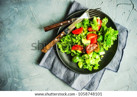 Oraganic vegetable salad with lettuce, cucumber, cherry tomatoes and flax seeds on rustic background with copy space
