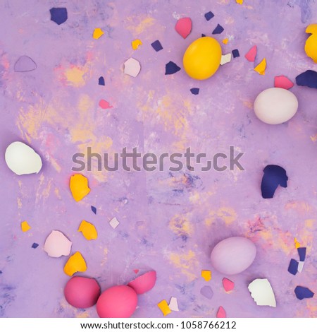 Top view of different colored eggs and scattered eggshell  on abstract background.
