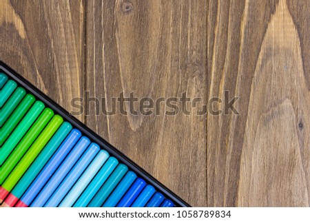 Collection of the colorful pencils, angled green and blue palette on the wooden background