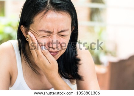Temporomandibular Joint and Muscle Disorder: TMD concept. Woman hand on cheek face as suffering from facial pain or toothache Royalty-Free Stock Photo #1058801306
