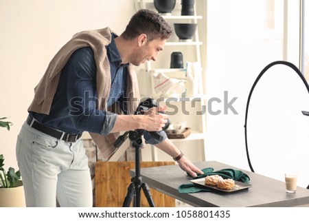 Young man with professional camera preparing food composition in photo studio