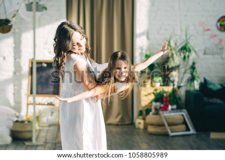 Mother is swinging daughter and smiling indoors. Happy to be together. Having fun. Royalty-Free Stock Photo #1058805989