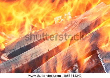 The wood burning in the grill to prepare delicious meats.