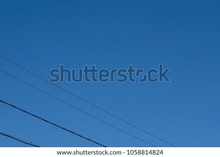 Wires and a flying airplane on a blue sky