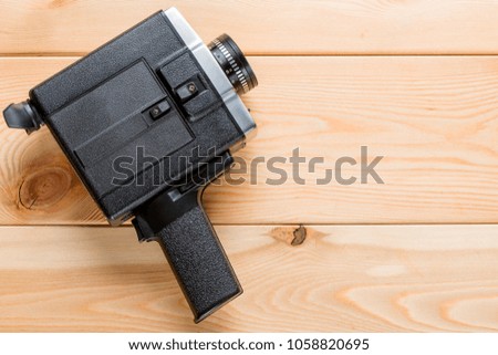 Vintage camcorder rests on light wooden boards, space on the right