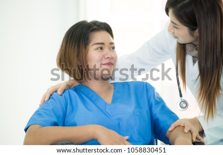 Obstetrician woman doctor is talking and supporting to a pregnant woman on wheelchair in hospital corridor,Asian woman doctor encourage in pregnant woman,Health care and empathy concept,