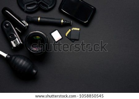 Photographers stuff on black background with lens flash cards lenspen cardrider