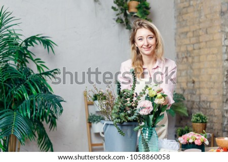 Image of florist woman in apron with bucket of flowers at table