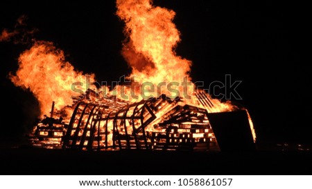 Wood crates burn on bonfire. Flames and silhouettes 
