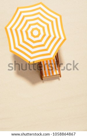 The concept of summer vacation. Top view on a sun lounger under an umbrella on the sandy beach Royalty-Free Stock Photo #1058864867