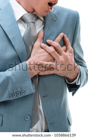 Close-up of young businessman having chest pain and heart attack, with hands holding the painful place.