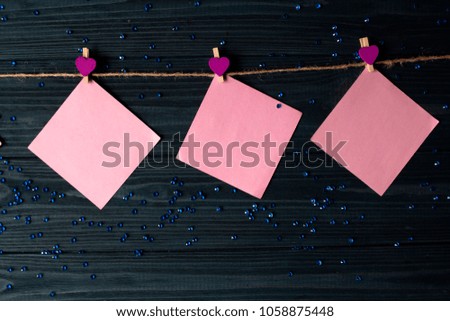 Pink memo sheets fastened with a decorative pin on a dark blue wooden board.