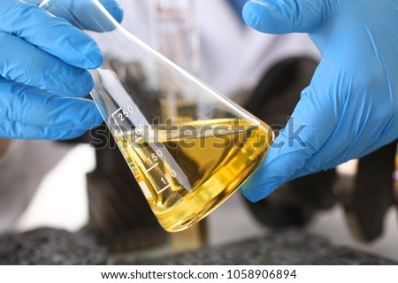 Male hands in protective gloves hold test tube in hands produces chemistry test of motor oil automatic gearbox and hydraulic booster Royalty-Free Stock Photo #1058906894