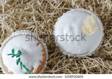 Easter pastry with butter 
cream and feathers on top, on bright hay background