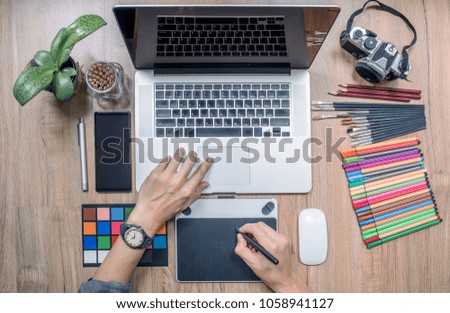 Top view of man designer using laptop computer and graphics tablet at home office. Professional occupation workplace