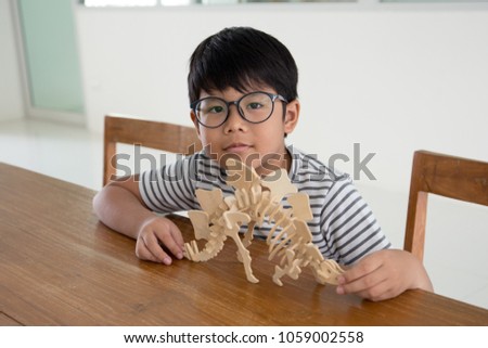 Happy Asian kid proud to finish making a 3D dinosour wood puzzle toy