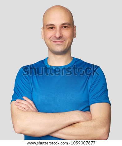 Cheerful guy smiles happily. Confident bald man dresssed casually with arms folded. Isolated over gray studio background Royalty-Free Stock Photo #1059007877