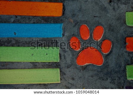 Unique design cement floor by using reusable orange dog footprint ceramic and multicolor cement flat bar shape on cement floor, cutie style of outdoor design in a garden space or living room 