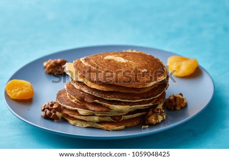 Pile of homemade pancakes with honey and walnuts on blue background, selective focus