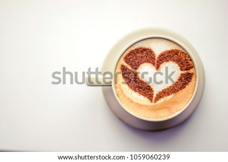 cozy cup of hot coffee in a white cup with a pattern of heart on milk foam