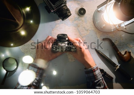 Adventure planning near gas lamp flat lay. Atmospheric old gear on map. Traveler, explorer hands in frame holding vintage film camera. Exploring, hiking photography, photographer concept.