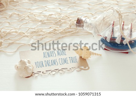 nautical concept image with sail boat in the bottle and note: ALWAYS MAKE YOUR DREAMS COME TRUE